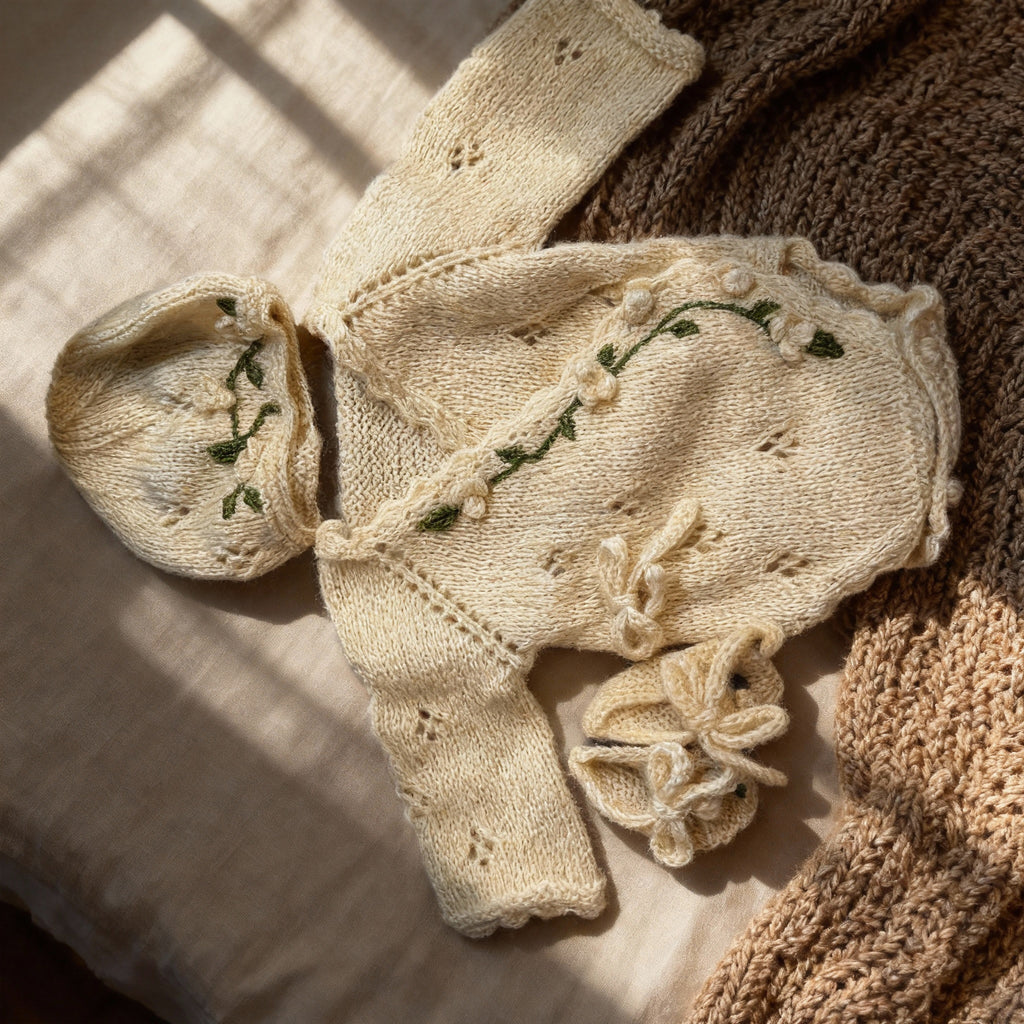 Handmade knit newborn clothes set featuring a beanie, romper, and booties with floral embroidery – the perfect newborn gift made with soft, premium cotton.
