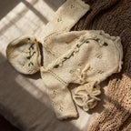 Handmade knit newborn clothes set featuring a beanie, romper, and booties with floral embroidery – the perfect newborn gift made with soft, premium cotton.