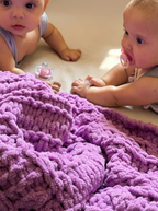 sophyia and faia playing with a soft, 100% handmade crochet baby blanket in vibrant purple, providing warmth and comfort – the perfect newborn baby gift.