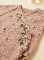 Close-up of luxurious knit newborn clothes with delicate floral embroidery, crafted from premium cotton – the perfect baby knitwear gift for your little one.