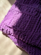 Close-up of a soft, 100% handmade crochet baby blanket in vibrant purple, crafted from premium cotton – the perfect newborn baby gift providing warmth and comfort.